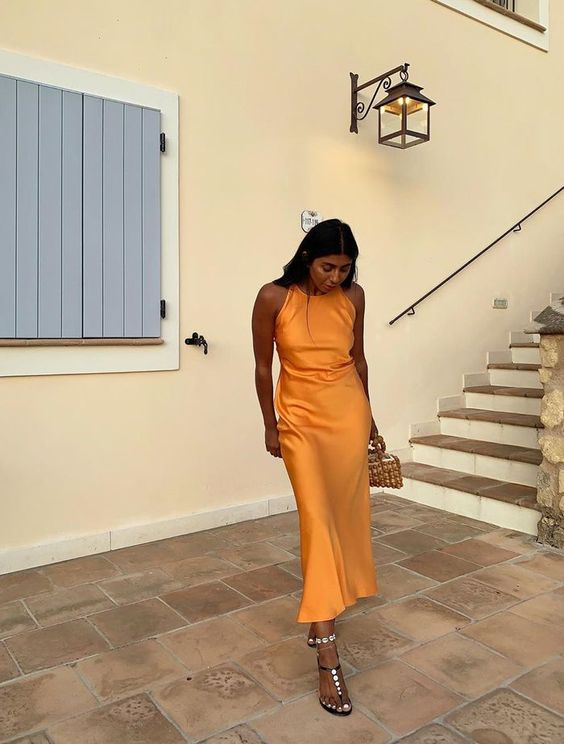 a satin orange maxi dress, embellished sandals, a small beaded bag are amazing for a beach wedding