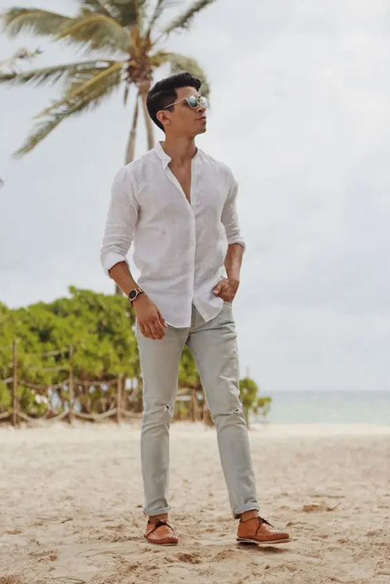 a simple beach wedding guest look with a white linen shirt, grey linen pants, brown shoes and sunglasses