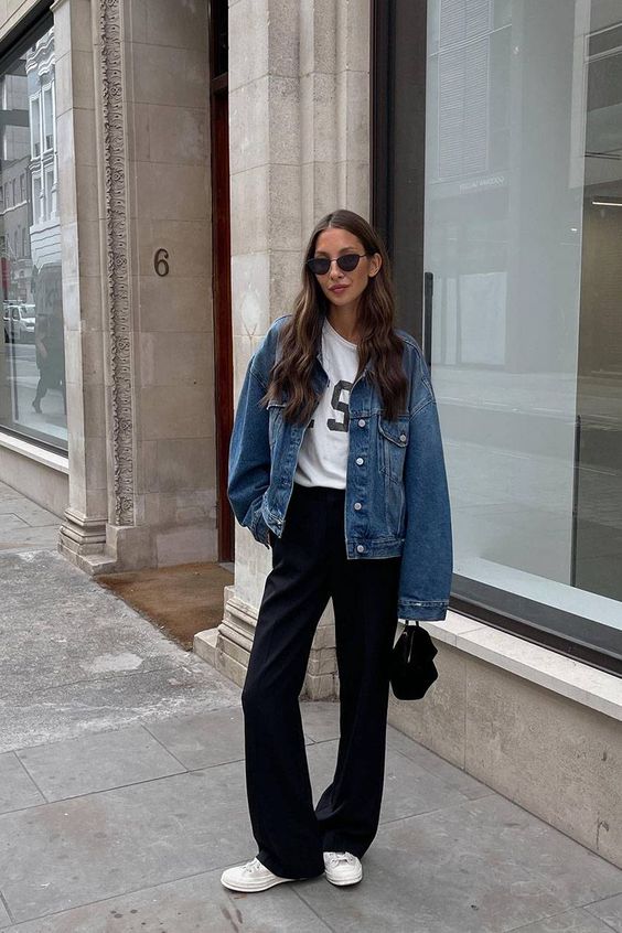 a simple spring outfit with a printed tee, black pants, white sneakers, a blue denim jacket and a black bag
