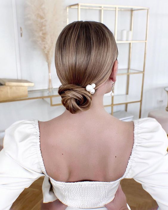a small sleek wrapped low bun with a sleek top and pearl hair pins is a chic idea for medium length hair