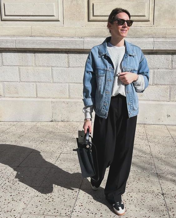 a spring look with a grey sweatshirt, black pants, sneakers, a black bag and a blue denim jacket