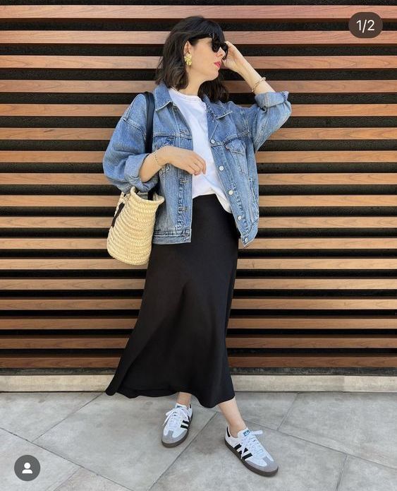 A spring look with a white t shirt, a blue denim jacket, a black midi skirt, white sneakers and a straw bag
