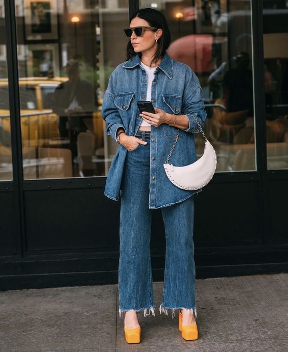 a spring look with a white top, a blue denim jacket, flare jeans, orange platform shoes and a white baguette bag