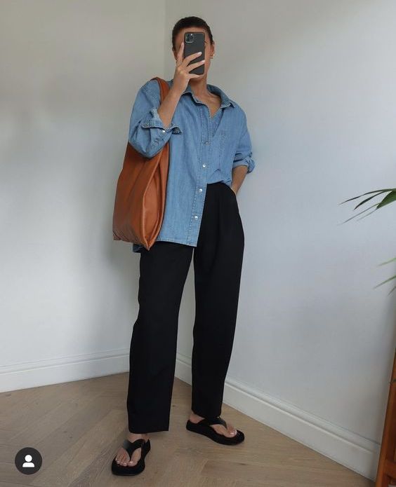 a spring to summer outfit with a blue denim shirt, black trousers, black slippers, an amber leather tote is cool