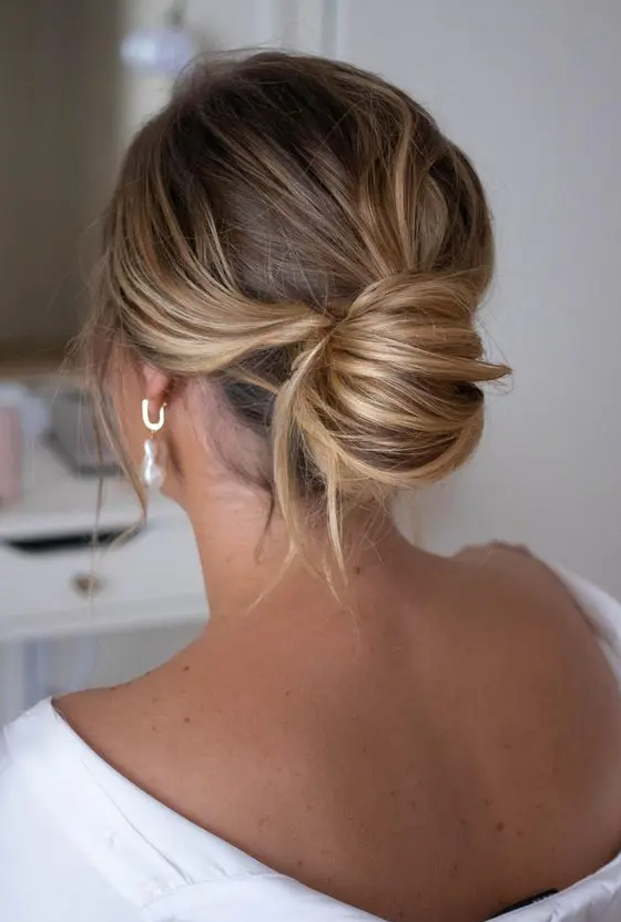 a stylish and chic messy chignon with waves on top and some locks down is a beautiful and elegant idea for a wedding