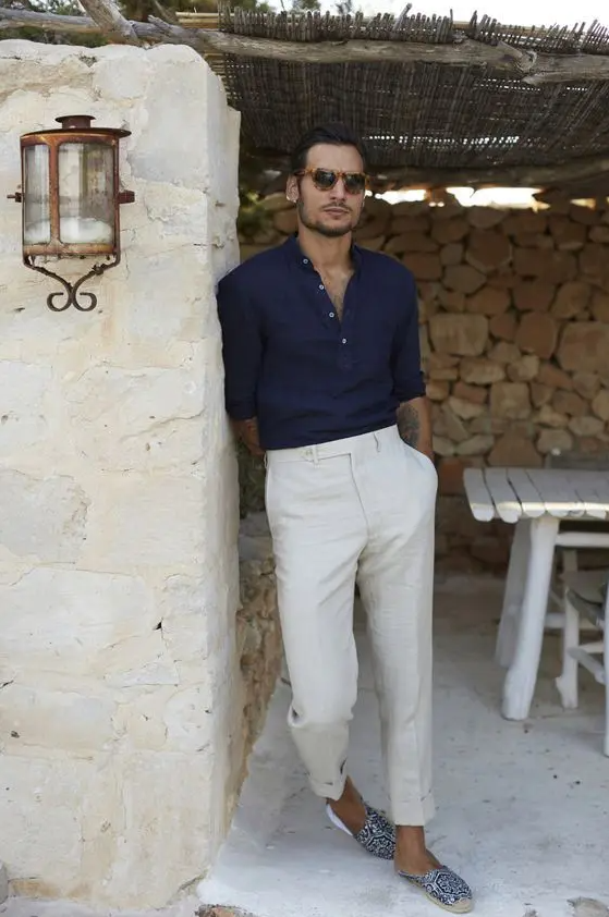 a stylish beach wedding guest outfit with a navy linen shirt, neutral linen pants, printed espadrilles