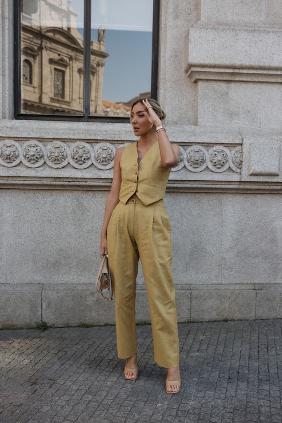 a summer wedding guest look with a yellow linen suit with a vest and pants, nude shoes, a small nude bag