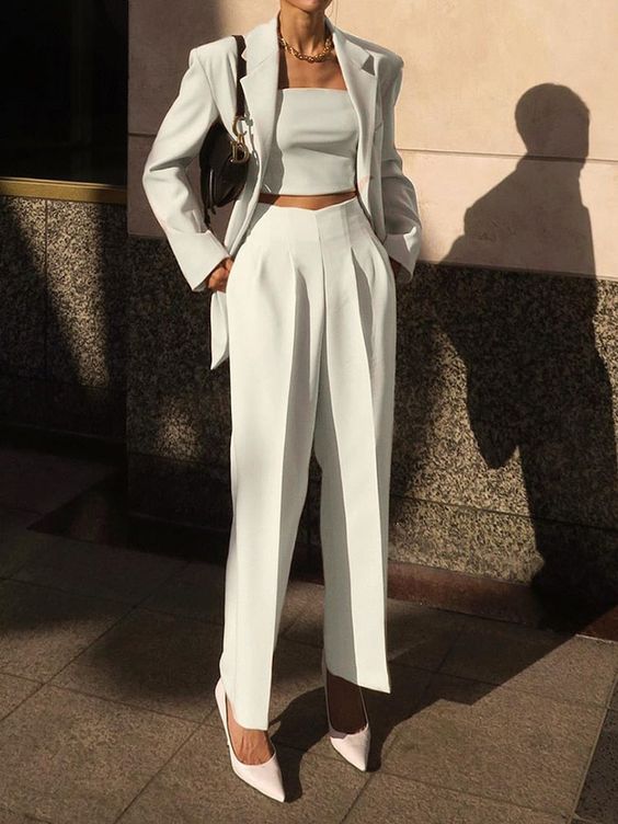 a super chic and elegant graduation look with a white pantsuit and a crop top, classic pumps and a black saddle bag for a stylish look