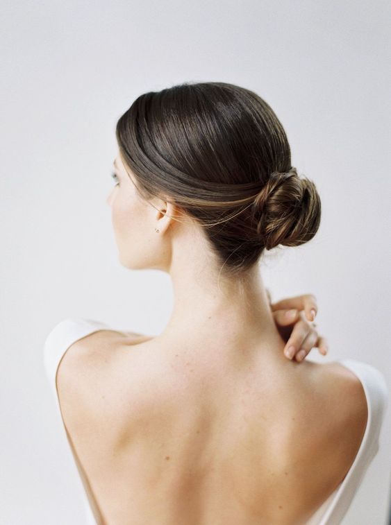 a twisted midi bun with a sleek top is a chic hairstyle for medium hair, great for a wedding