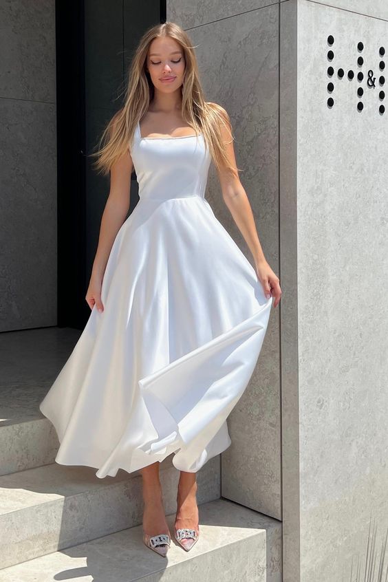 A white A line midi dress with straps and a square neckline, nude shoes are a chic and feminine look for graduation
