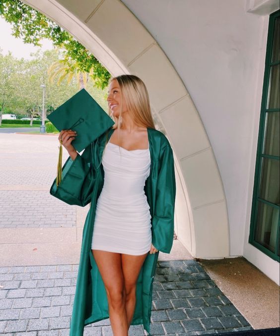 a white draped mini dress, a green robe and cap are a cool and sexy look for any graduation