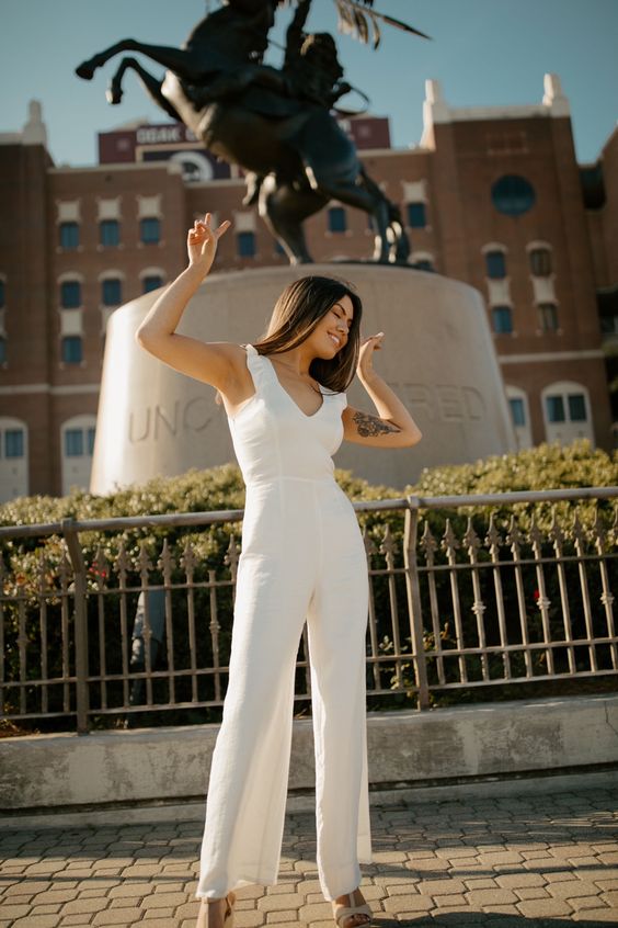 a white jumpsuit with ruffle straps, a V-neck and nude shoes are a cool and lovely combo for graduation