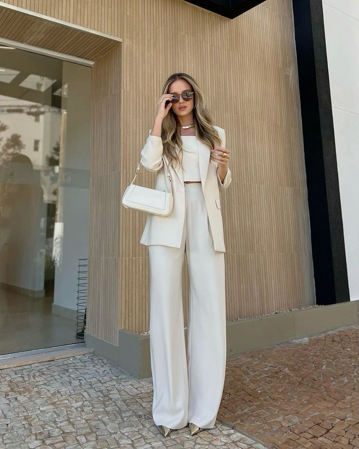 a white pantsuit with a crop top, pants and a blazer, gold shoes and a small bag plus a necklace for a refined and chic graduation look