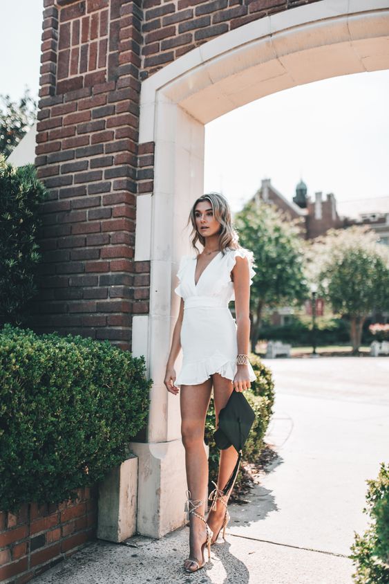 a white ruffle mini dress, lace up heels, a bracelet and a cap are a sexy and bold look for graduation