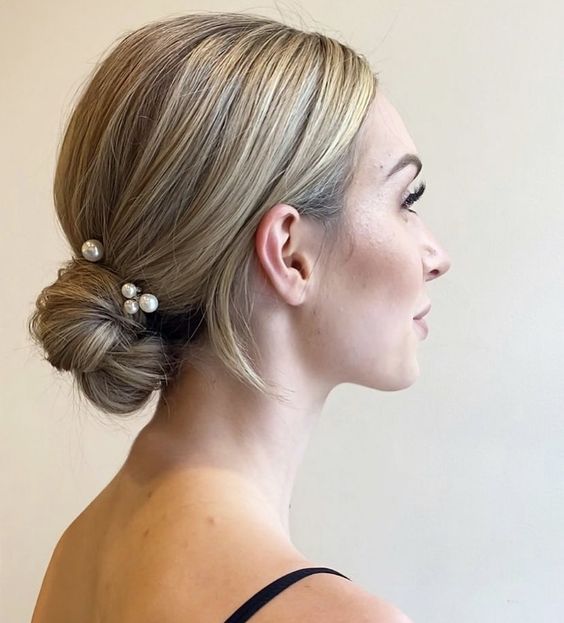 a wrapped low bun with a sleek top and pearl hairpins is a pretty wedding hairstyle for medium hair