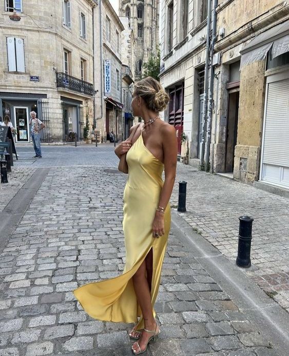 a yellow satin maxi dress with a loop on the neck, silver strappy shoes and a nude baguette bag are amazing for a beach wedding