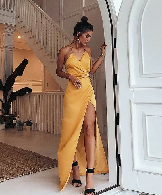 a yellow wrap maxi dress with spaghetti straps, black ankle strap shoes and statement earrings for a beach or tropical wedding
