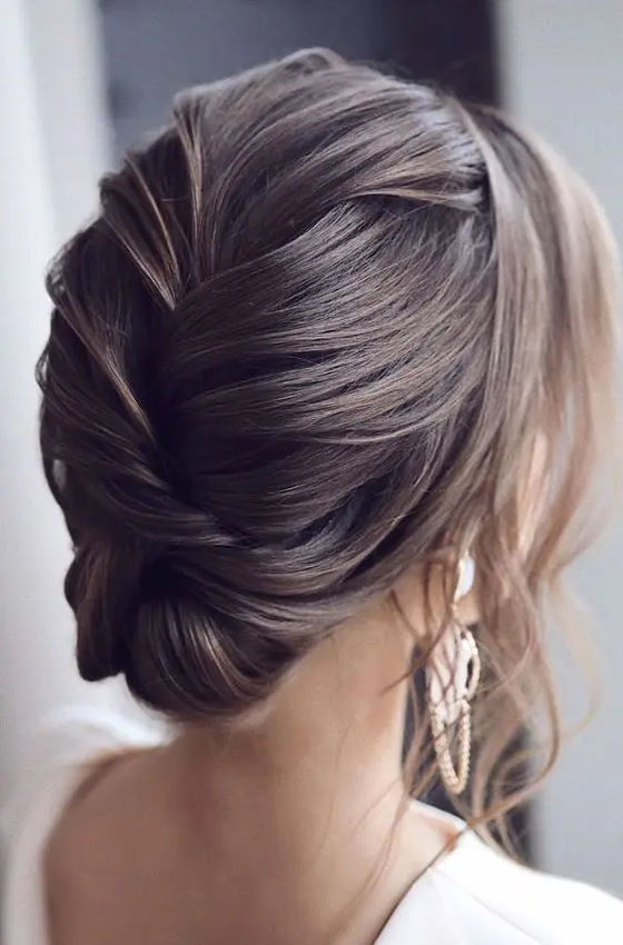 an elegant and sophisticated wedding updo with a braided back with volume and some locks framing the face is a cool and chic idea