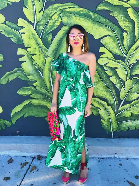 one shoulder tropical leaf print maxi dress with a side slit, hot pink wedges and a bright printed clutch plus tassel earrings