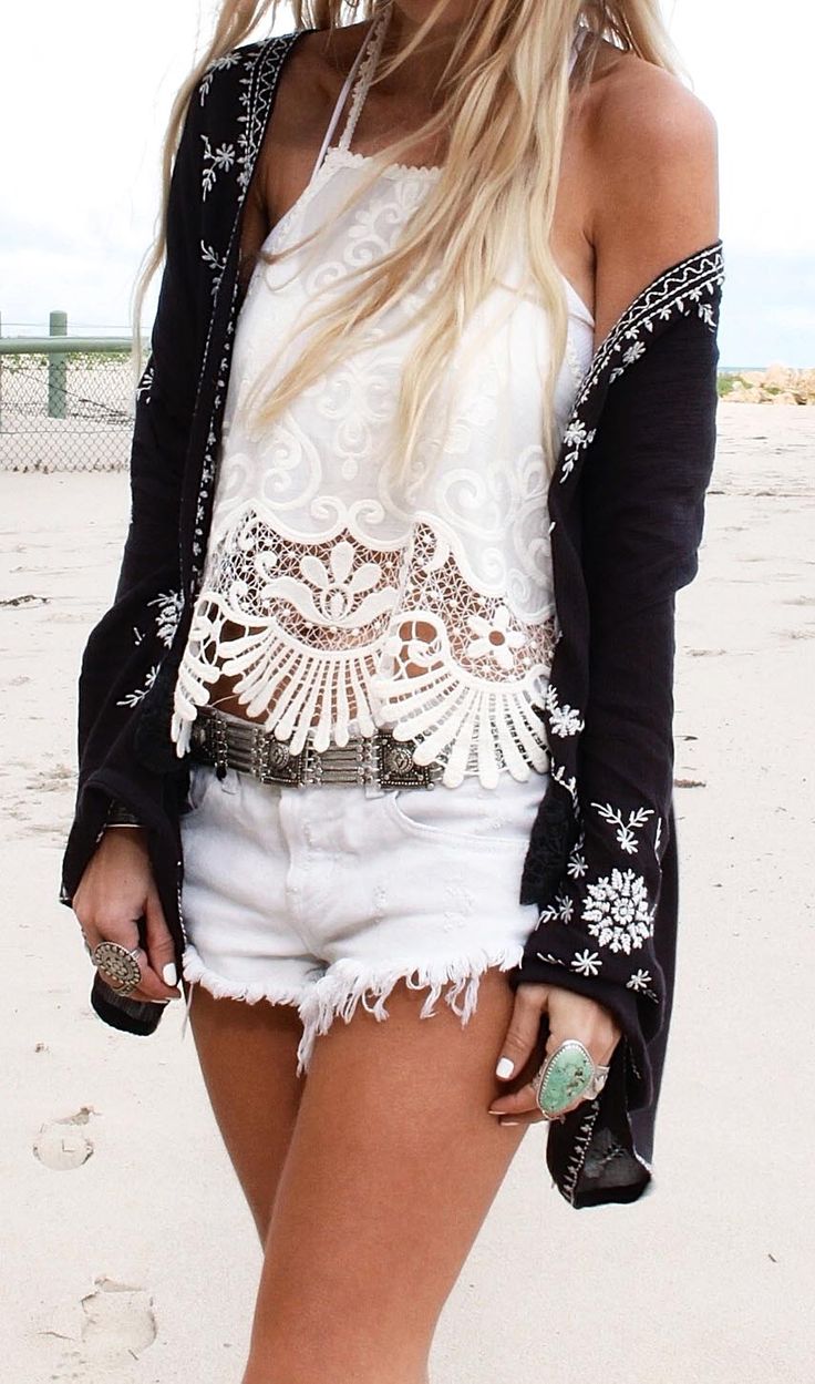 A monochromatic boho outfit with a white lace top, white denim shorts and a black coverup with white embroidery