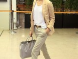 a neutral outfit with grey pants, a white top, embellished flats, a camel blazer and a grey tote