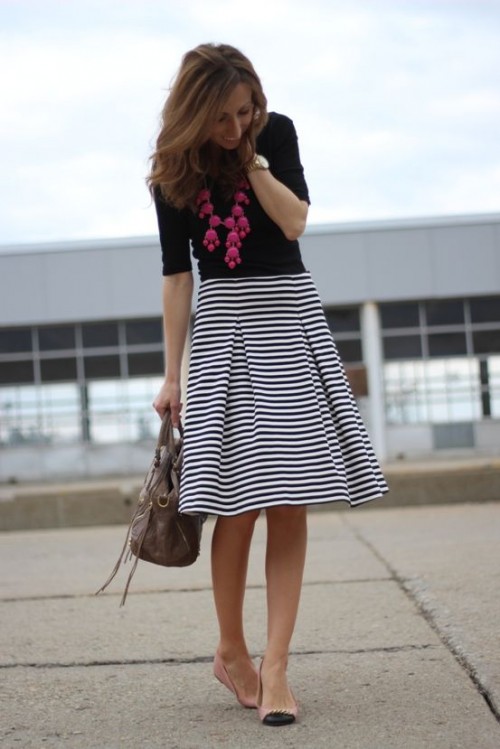 a black top, a striped midi, a statement pink necklace, blush and black flats and a grey bag