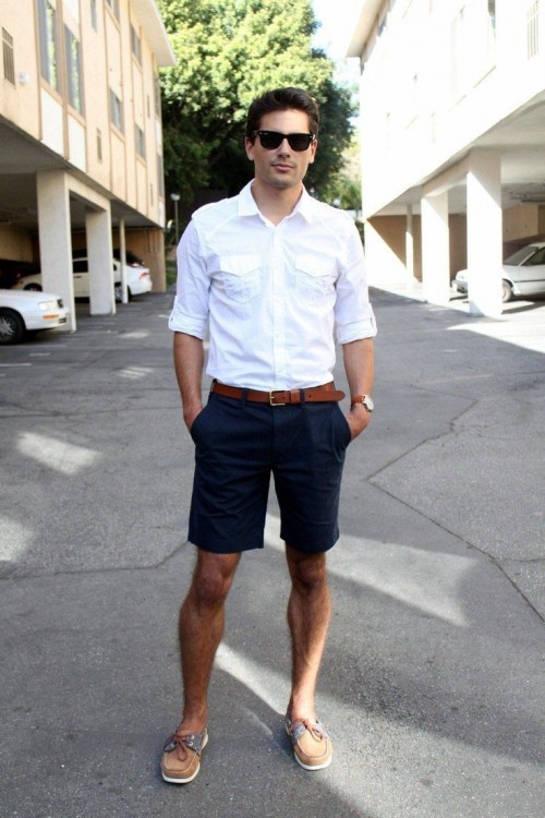 a light summer work look with long navy shorts, a white shirt with rolled up sleeves, brown shoes