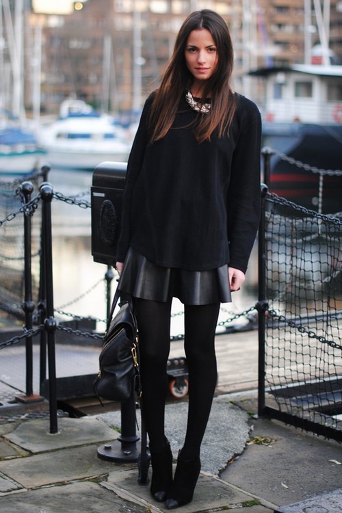 a black leather mini, a black oversized sweatshirt, a statement necklace, black booties and a black bag catch an eye